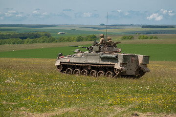 British army Warrior FV510 light infantry fighting vehicle tank in action on a military exercise, blue sky with light clouds, Wiltshire UK