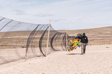 men placing fence for the realization of chaco de vicuñas in the Andes mountain range on a sunny...