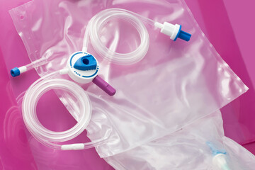 Devices for daily self-care CAPD (continuous ambulatory peritoneal analysis) treatment. Tubing system and drainage bag on dialysate bag on pink background - obrazy, fototapety, plakaty