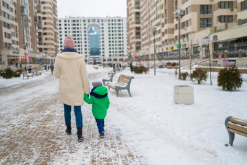 mother and son walk through the city in winter.