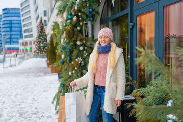girl going out of the store with purchases on the background of Christmas fir. sale