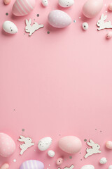 Top view vertical photo of easter decorations shiny confetti easter bunnies lilac pink and white easter eggs on isolated pastel pink background with empty space
