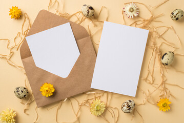 Top view of big brown craft envelope with two postcards five eggs with brown spots different size and cute yellow and white flowers situated on straw on beige background