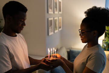 Creating family traditions. Young happy black couple hold little homemade pie with berries while celebrating their 5th Anniversary as special milestone in life, african family celebrate special date