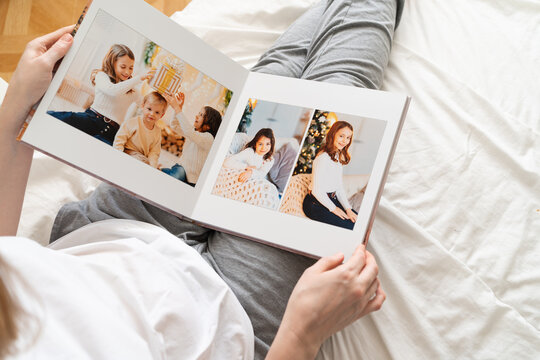 top view woman holds photobook in hands while sitting in bed.family photo shoot 