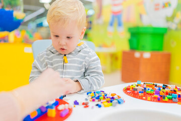 little boy play colorful cubes puzzle at the table