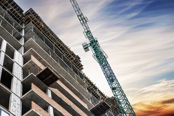 Construction crane on the construction of a monolithic house on a background of beautiful sky