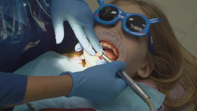 kid girl with oral dilator at dentist's appointment. polishing of teeth
