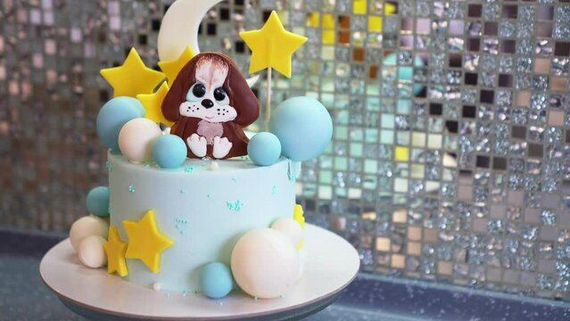 blue cake decorated with balls, stars and puppy made of mastic and chocolate.