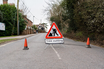 Tree cutting safety sign and orange cones blocking off road to keep the general public safely away from the danger zone from falling branches and machinery that is in use