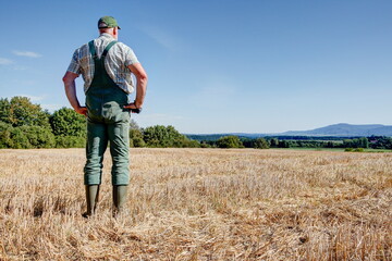 After the harvest, a farmer stands on his mown grain field and enjoys the view over the vast country to the foothills of the Swabian Alb.