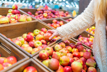 female hands take apples in a store in wooden boxes
