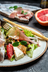 Prosciutto crudo ham salad with brie camembert cheese and grapefruit, salad mix. Restaurant menu, dieting, cookbook recipe