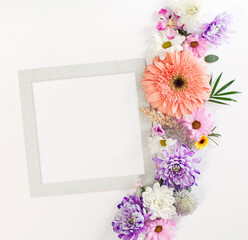 Various flowers composition on flat lay white background with a silver frame in a soft light square design.