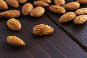 Macro of almonds on dark wooden table. Organic health protein vegetarian food. Background copy space
