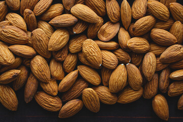 Close up almonds on dark wooden table. Organic health protein vegetarian food concept. Background