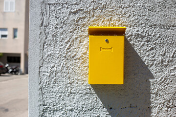 Yellow mailbox on the wall at sunny day. Box for letters and correspondence