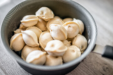 Cooking pot with frozen traditional Russian dumplings pelmeni filled with meat for boiling closeup macro