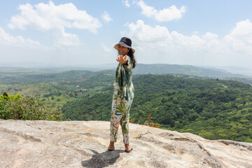 Mulher se vislumbra com a paisagem no alto da montanha. 