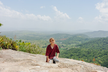 Menina no topo de uma pedra alta