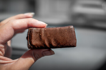 Hand holding eating storebought Russian tasty cheesecake candy bar from Russia with chocolate glaze...