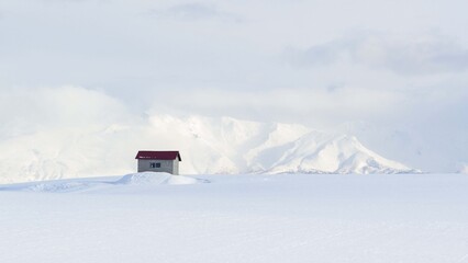 北海道・美瑛町 冬の丘に佇む小屋と背後に聳える十勝岳の風景