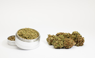 Close-up of medical marijuana buds, aluminum grinder, white background