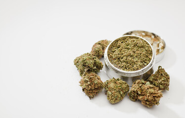 Close-up of medical marijuana buds, aluminum grinder, white background