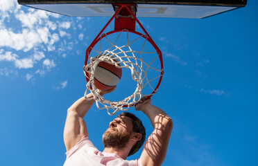 slam dunk in motion. summer activity. jumping man with basketball ball on court. © Olena