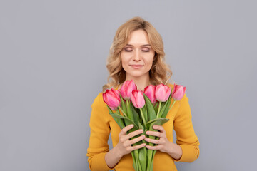 glad woman smell tulips on grey background