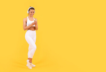 Naklejka na ściany i meble sport woman with headphones and smartphone on yellow background. copy space