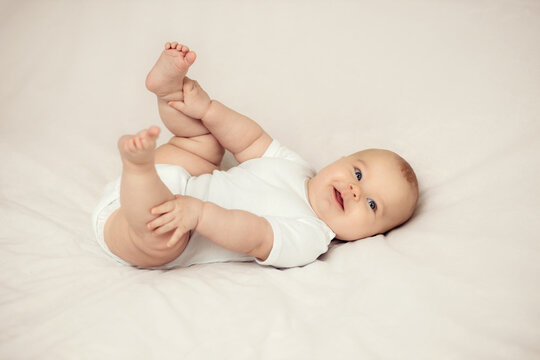 Portrait of a cute little baby girl lying on white sheets at home.