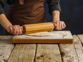 Cooking dough on a wooden cutting board by a professional chef. Restaurant, hotel, bakery, pizzeria, pastry shop, home cooking, advertising, banner.