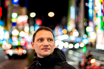 Tokyo, Japan Shinjuku downtown ward district at night with young man portrait looking at nightlife...