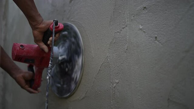 A construction worker is working using an automatic plastering machine to plaster the walls, use of modern technology and electric tools in construction work