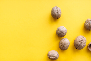 Several whole walnuts on a bright yellow background closeup, flatlay
