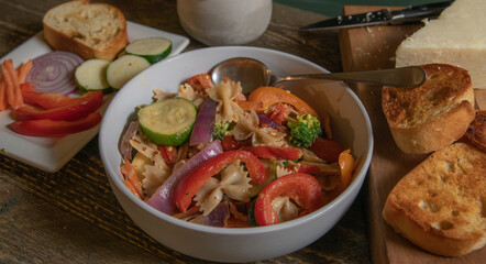 Pasta Salad With Parmesan Cheese and Garkic Bread on Wood Table Top