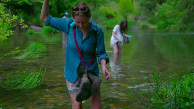 Hikers wade across flooding river