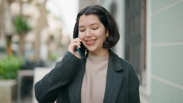 Young hispanic girl smiling confident talking on the smartphone at street