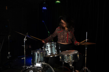 Fototapeta na wymiar beautiful Chinese drummer playing drums in a nightclub 