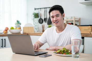 Portrait of Asian business man eat healthy salad while work from home. 
