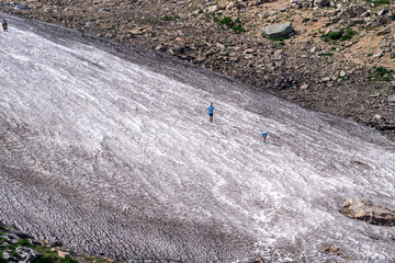 Unrecognizable hikers traverse the glacier at St. Mary's Glacier Colorado during the summer