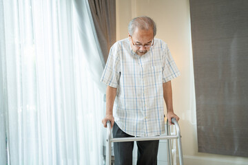 Asian Senior elderly man patient walking slowly with walker in house. 