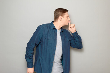 Portrait of serious strict mature man showing silence gesture