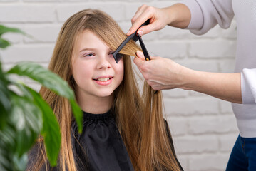 Hairdresser making a hair to cute girl in hair salon. Young girl at hairdresser. beauty salon concept