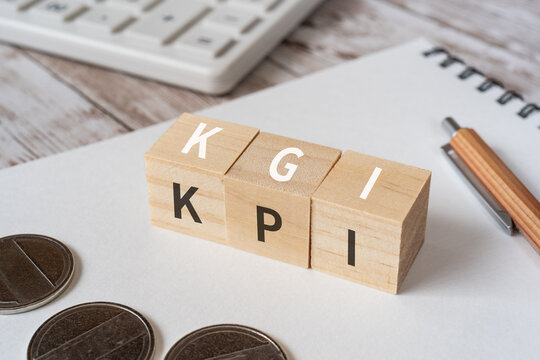 KGIとKPIのイメージ｜「KGI」「KPI」と書かれた積み木、コイン、ノート、電卓、ペン