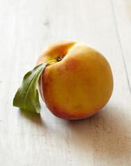 Single Peach with Leaf on White Wooden Surface