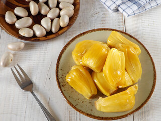 Already peeled Fresh and sweet prime jackfruit or nangka in Indonesian served on a plate with its edible seeds on the background. 