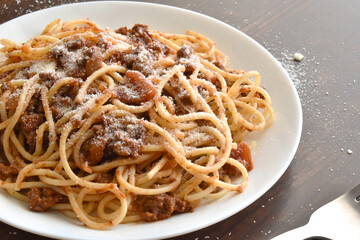 Spaghetti Bolognese with minced beef, onion, chopped tomato, garlic, olive oil, stock cube, tomato puree and Italian herb. Traditional Italian food in white plate.