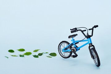 Fototapeta na wymiar World bicycle day. Bicycle emitting fresh green leaves on blue background. Sustainable and healthy concept